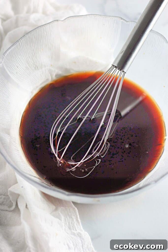 Sauce being mixed with a whisk in a glass bowl.