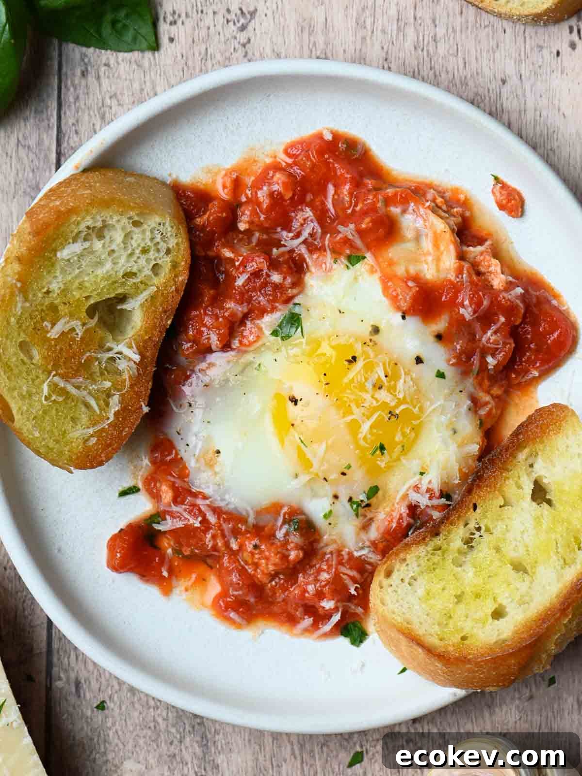 Overview of eggs, sauce and bread on a white plate.