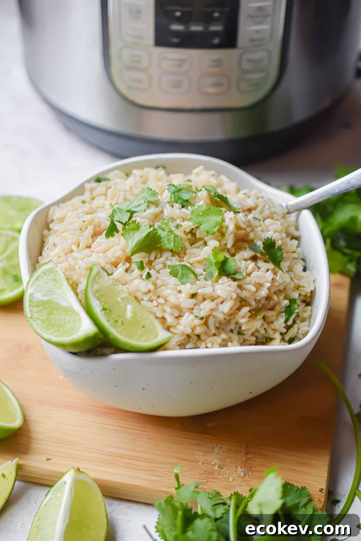 A bowl of cilantro lime brown rice is in front of the Instant Pot topped with pieces of lime.