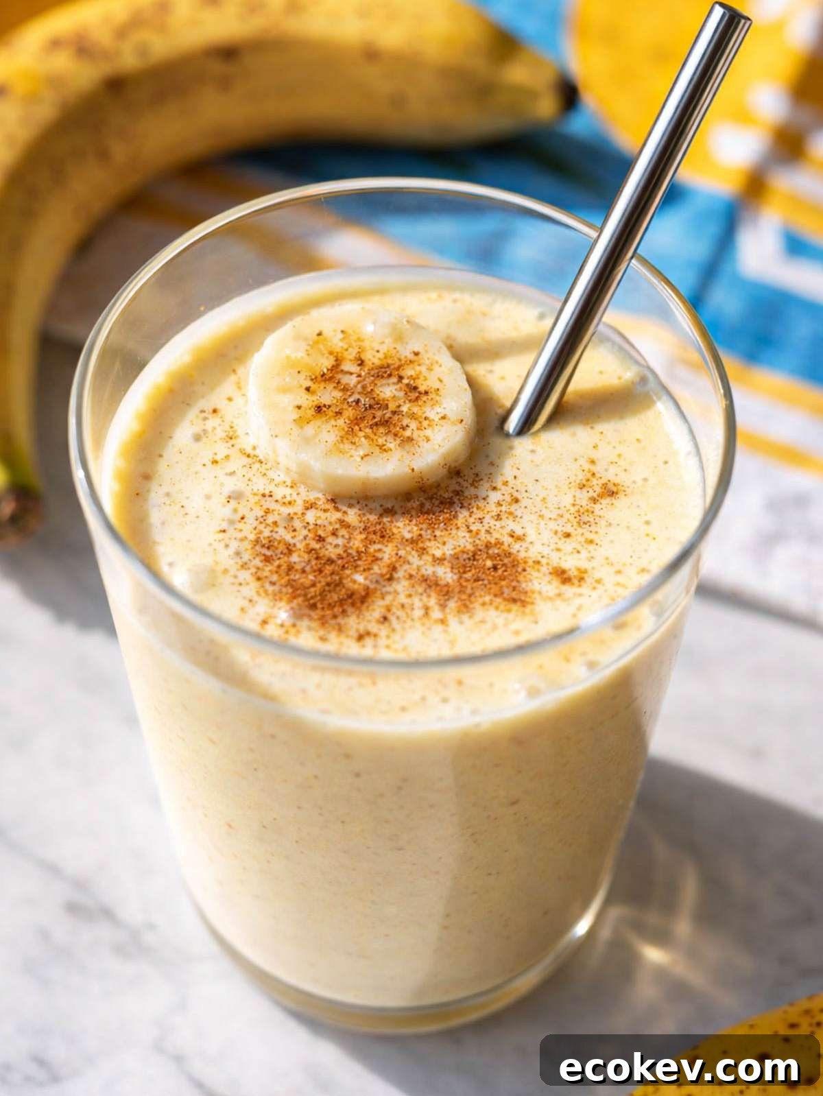 Glass of Greek Yogurt Banana Smoothie on marble surface near bright window.