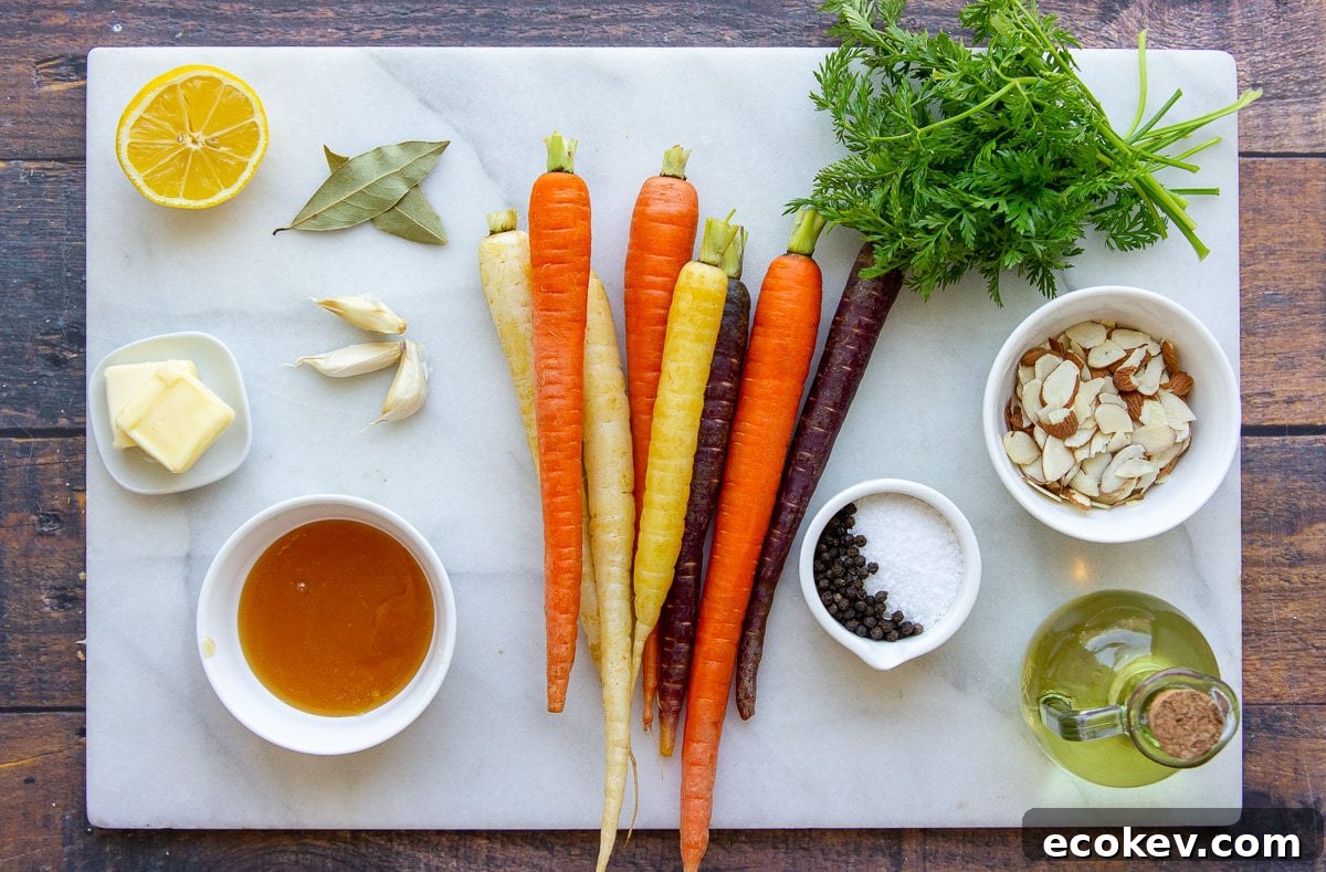 a pile of rainbow carrots, carrot greens, almonds, garlic, lemon juice, and other ingredients on a white granite cutting board.