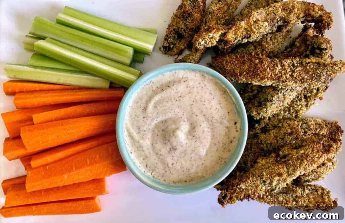 Portobello fries on a plate with stone-ground mustard dipping sauce and carrots and celery.