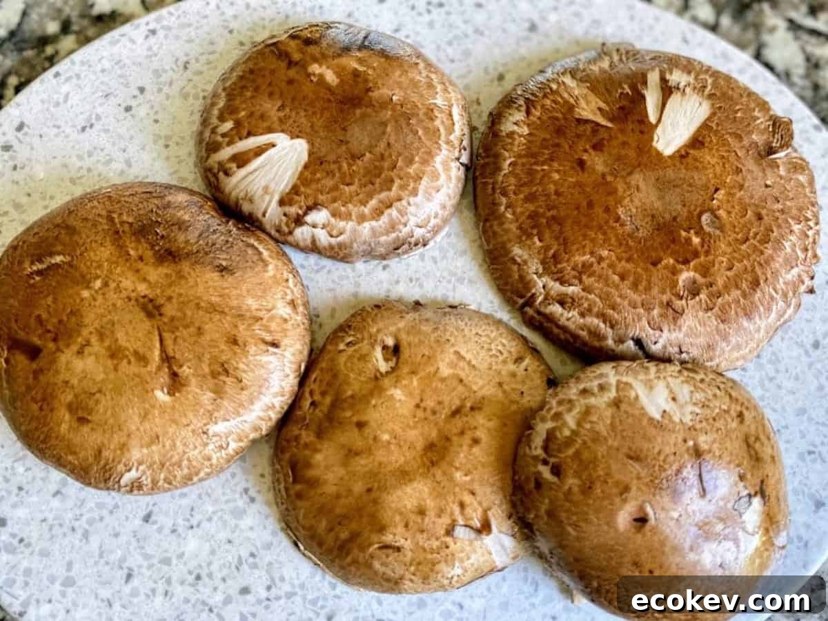 Large cleaned portobello mushrooms on a cutting board.
