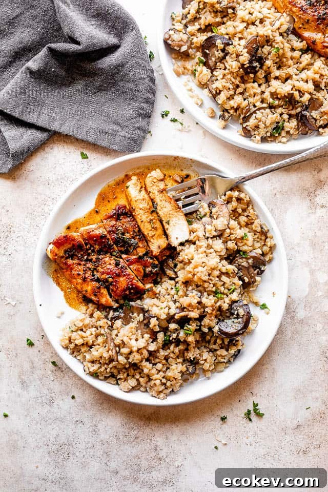 cut up chicken breast on a white plate with a side of cauliflower rice 