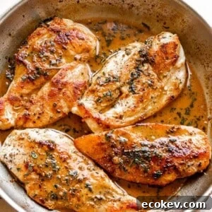 four chicken breasts cooking in a stainless steel skillet