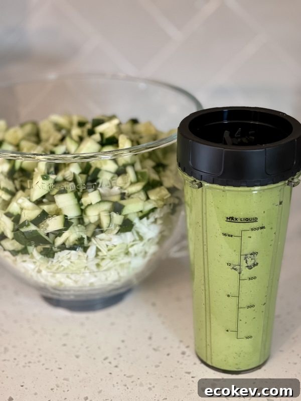 Tiktok's Green Goddess Salad in a glass bowl next to the blender with the dressing.