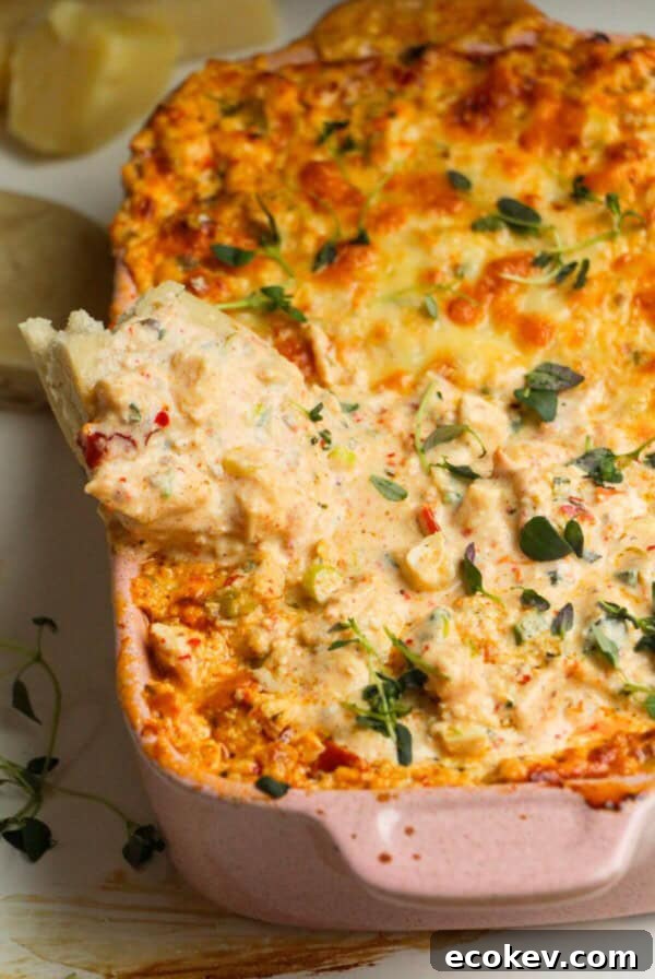Pita bread dipped into baked dip in a baking dish.