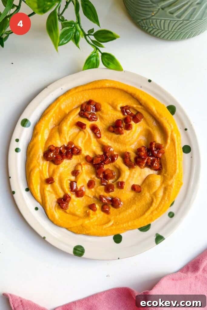 Chorizo on top of butternut squash feta dip on plate.