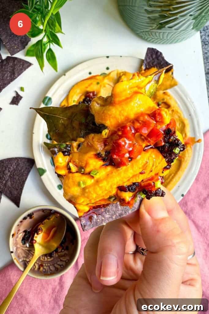Holding tortilla chip with butternut squash feta dip on it.