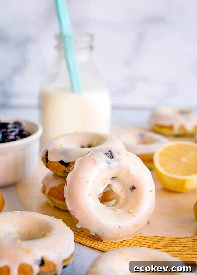 a lemon blueberry donut propped up against a stack of donuts with milk behind it