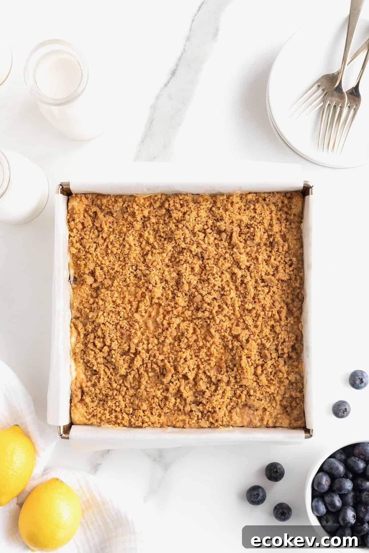 A streusel topped dessert in a baking pan lined with parchment paper.