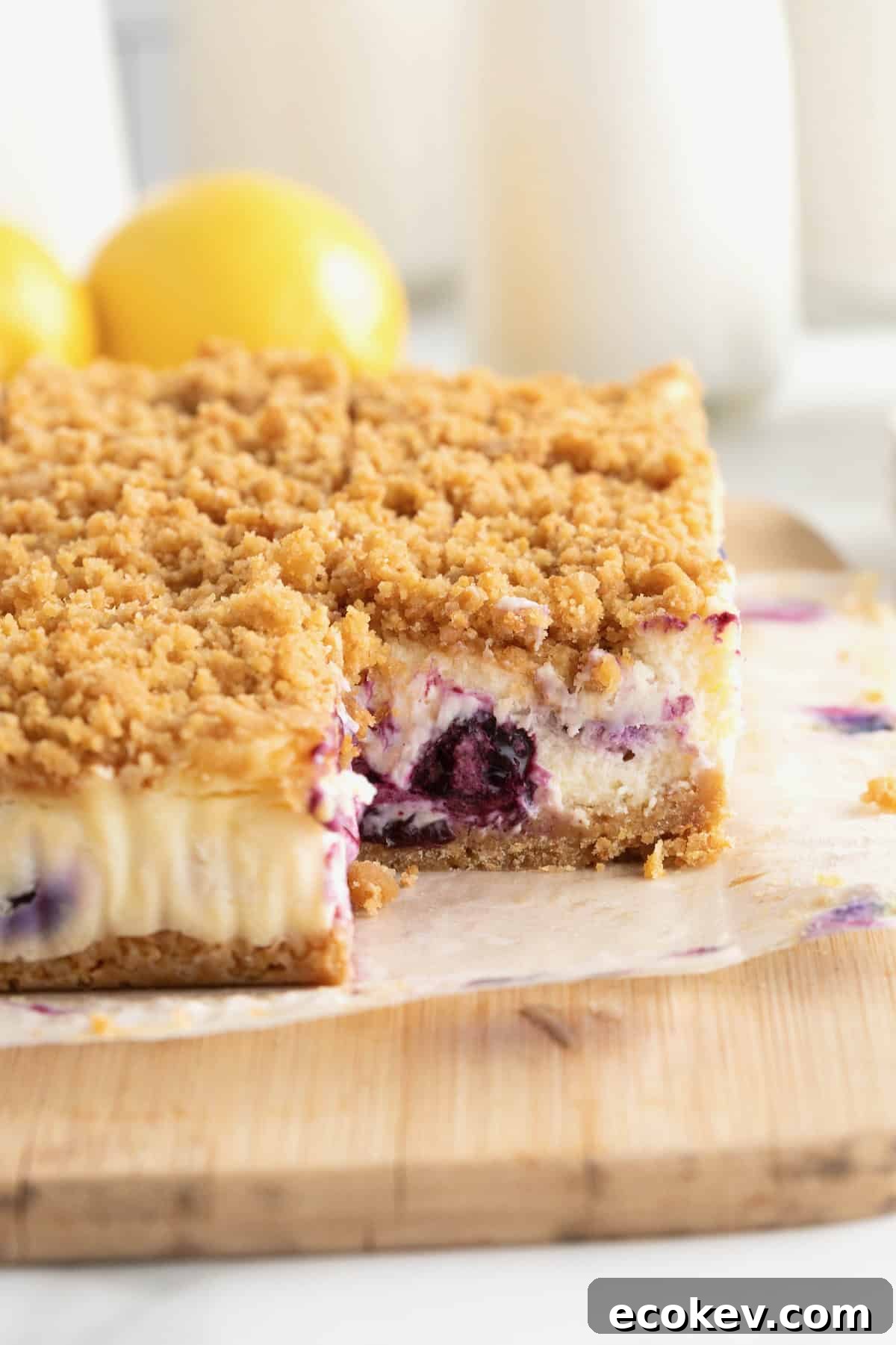A side view of lemon blueberry cheesecake bars on a parchment lined cutting board.