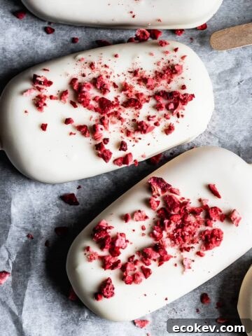 Closeup of strawberry rhubarb ice cream bars covered in white chocolate with freeze dried strawberry bits sprinkled on top