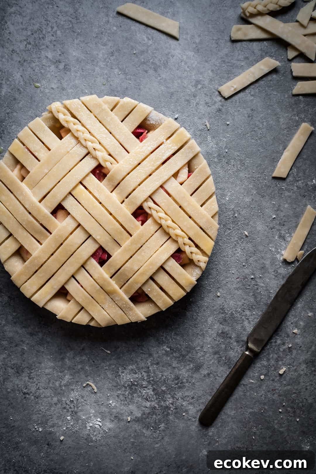 close up on a grey surface of rhubarb apple pie with ginger and lemongrass with lattice top including a small braid of dough