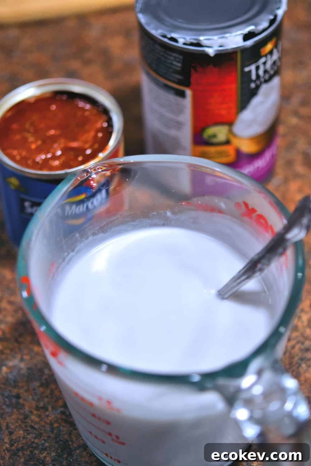 a measuring cup full of coconut cream which has been briskly stirred together to incorporate the solids and liquids