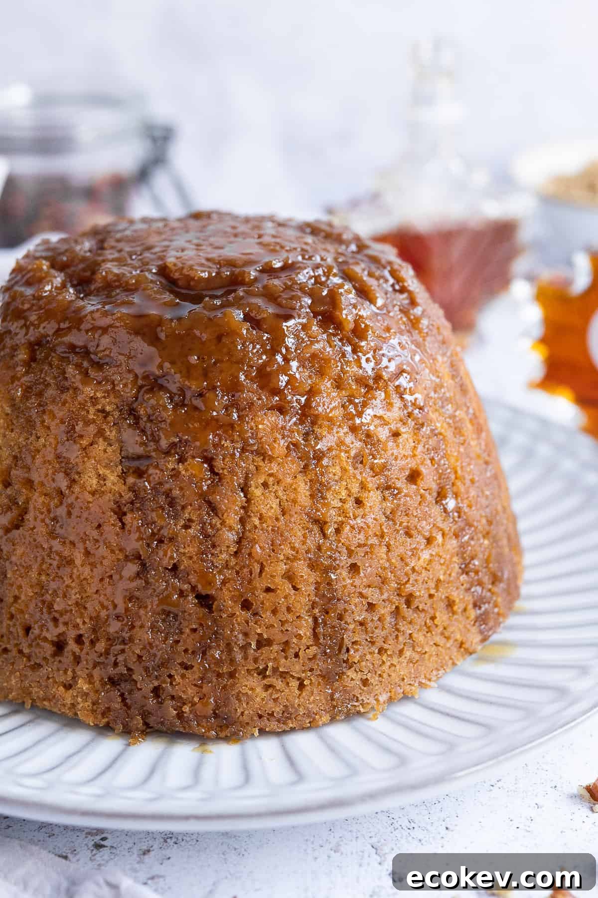 Close up of vegan steamed maple syrup pudding topped with a drizzle of maple syrup.