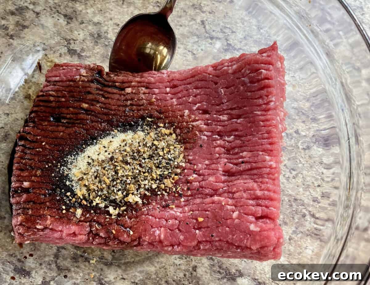 Ground beef and seasonings in a clear large mixing bowl.