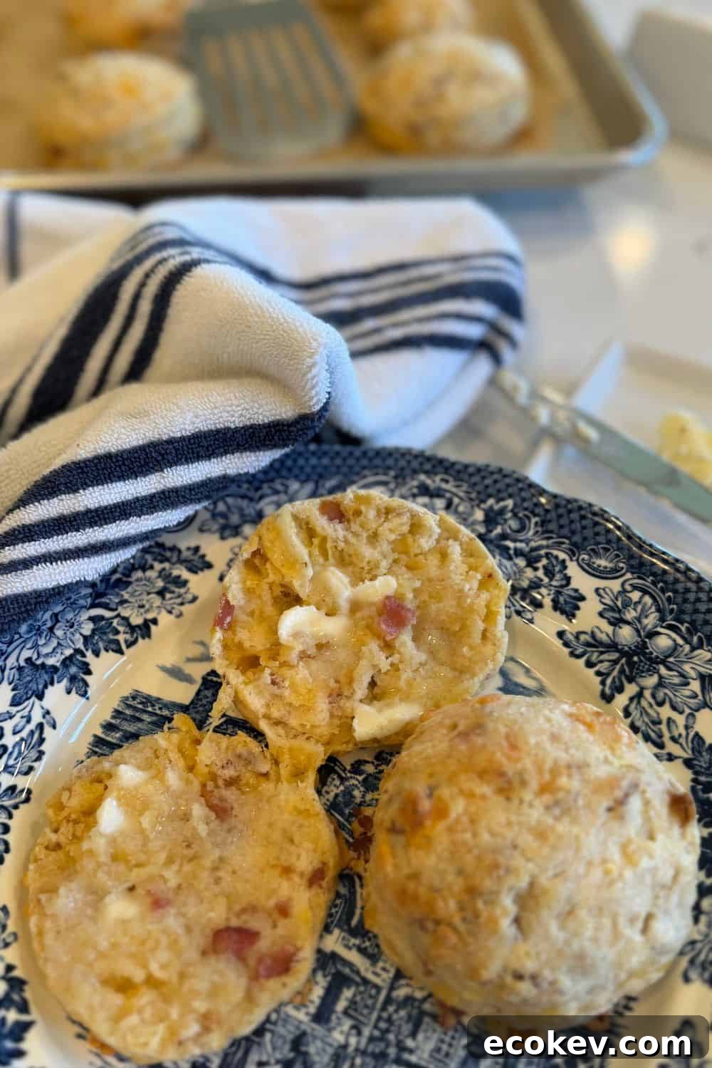 bacon cheddar sourdough biscuits on a plate sliced with butter