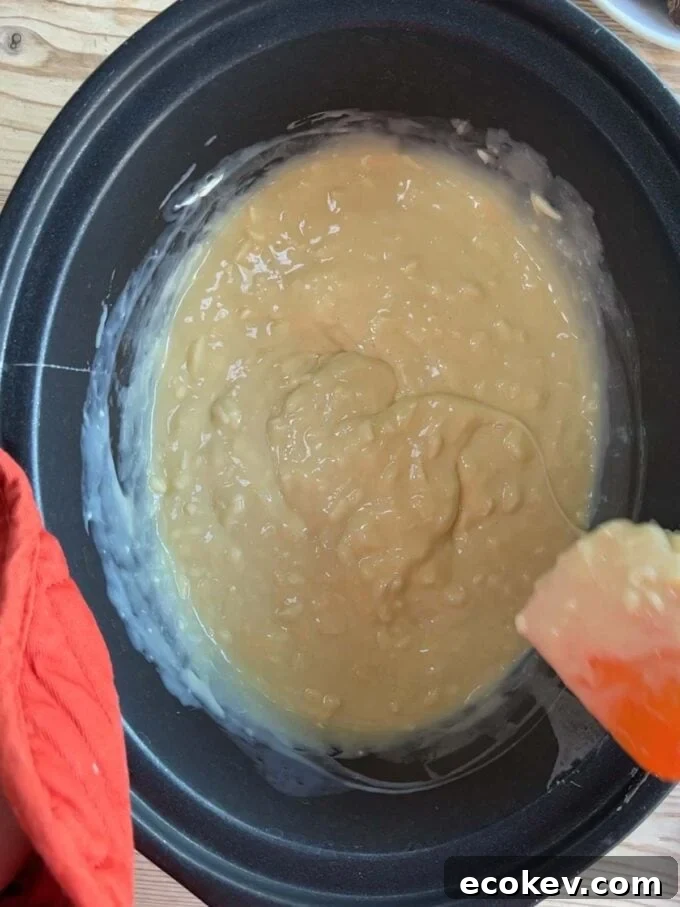 A slow cooker with melted white chocolate and condensed milk. Rolo Fudge recipe. Step 2.