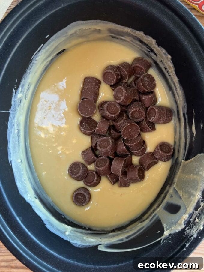 A slow cooker with melted white chocolate and condensed milk and rolos. Rolo Fudge recipe. Step 3.
