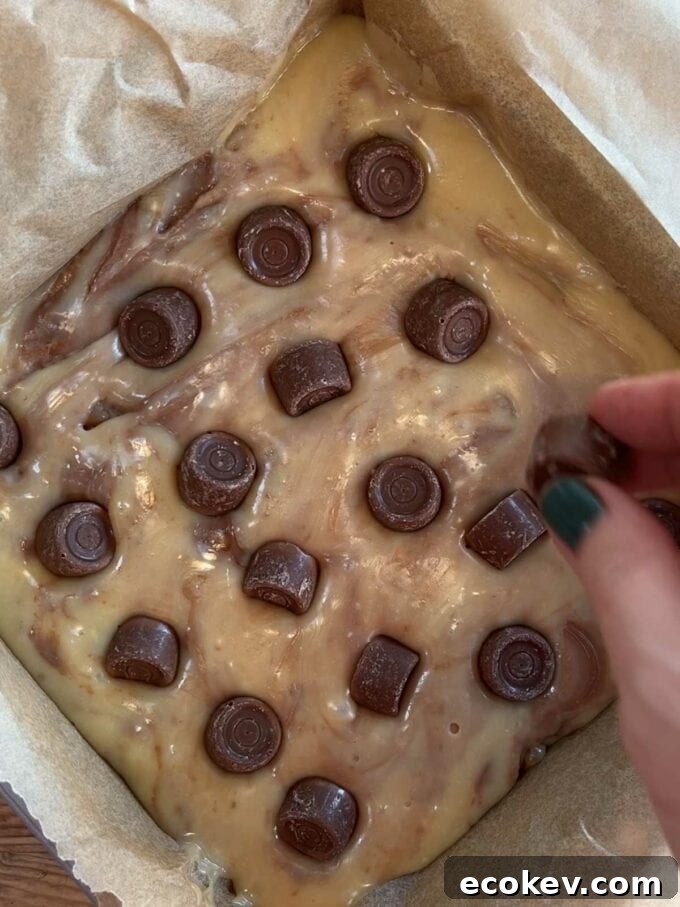 Chocolate mixture and rolos poured into a tray for the recipe Rolo Fudge. Step 4.