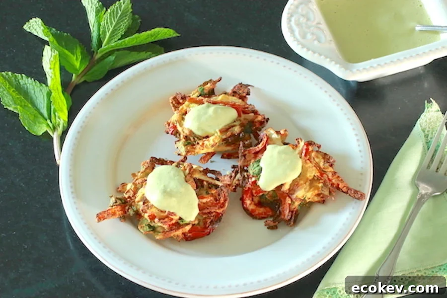 Three cooked pakora topped with Creamy Cashew Sauce and Dressing with a sprig of mint leaves to the side