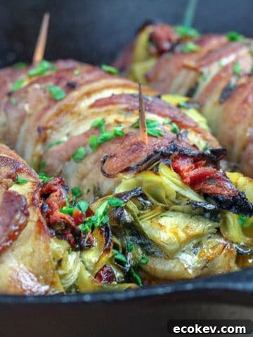Bacon wrapped stuffed chicken on a skillet.