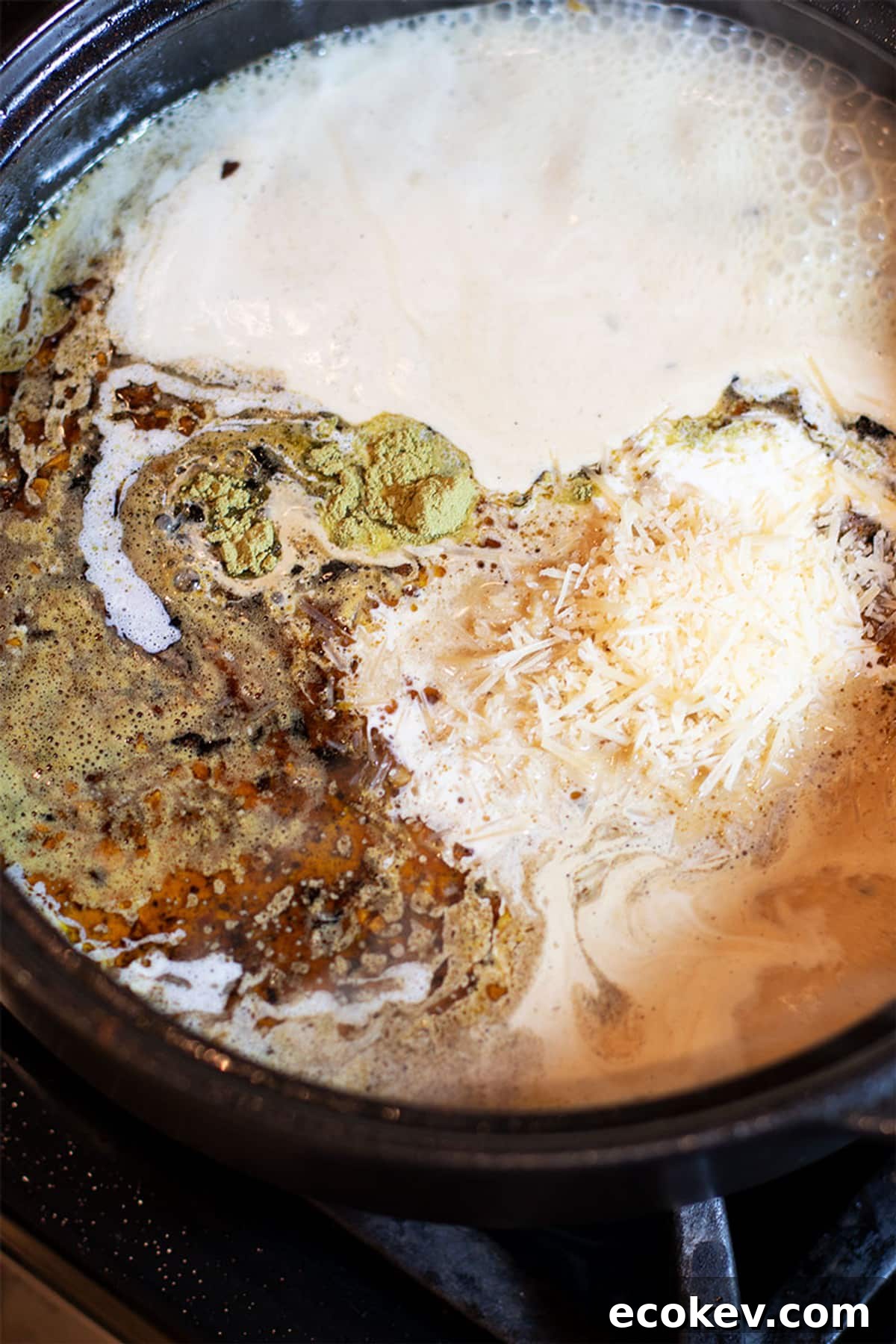 Lemon butter cream sauce in a black pan containing thyme, Parmesan cheese and heavy cream.