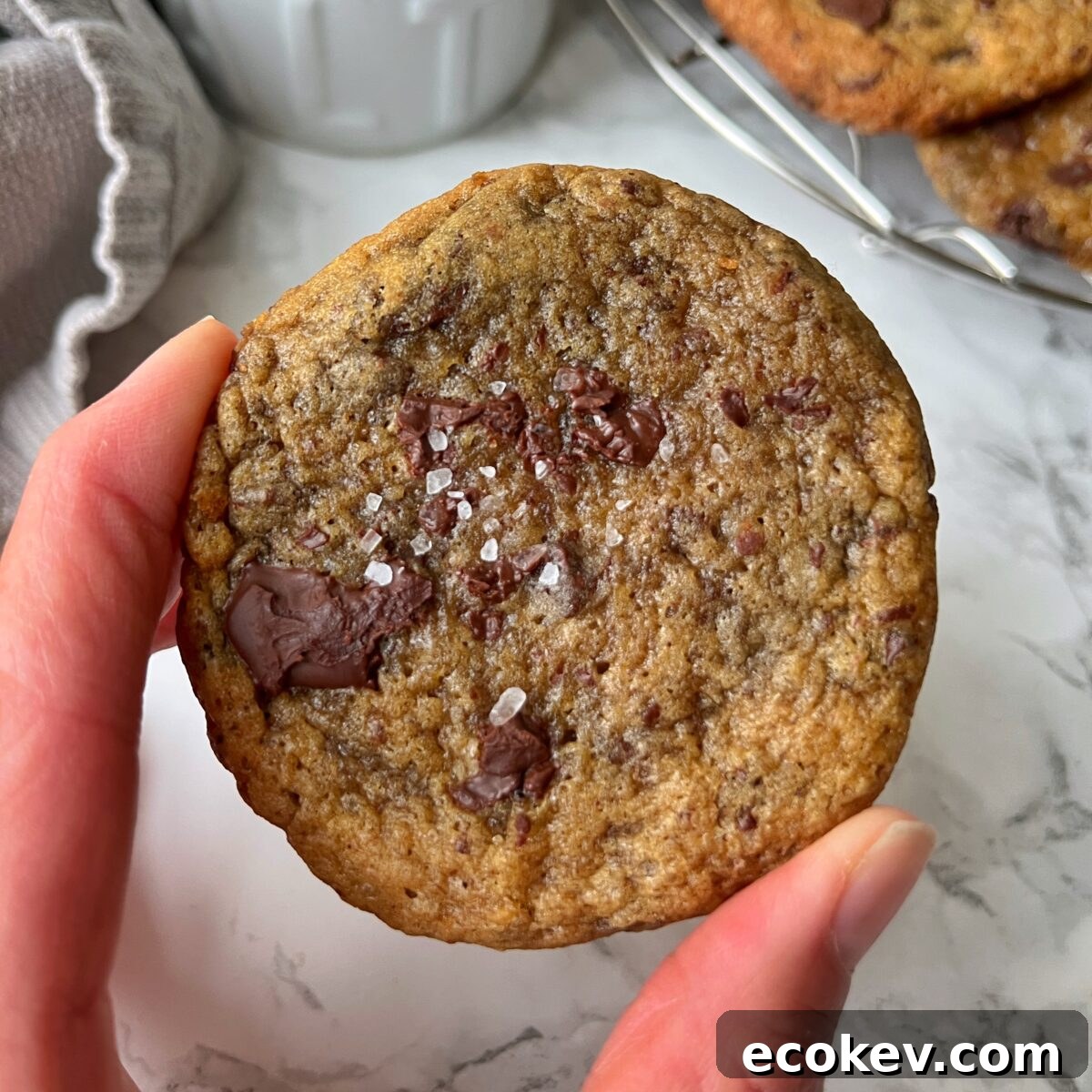 A hand holds a banana bread cookie topped with coarse sea salt.