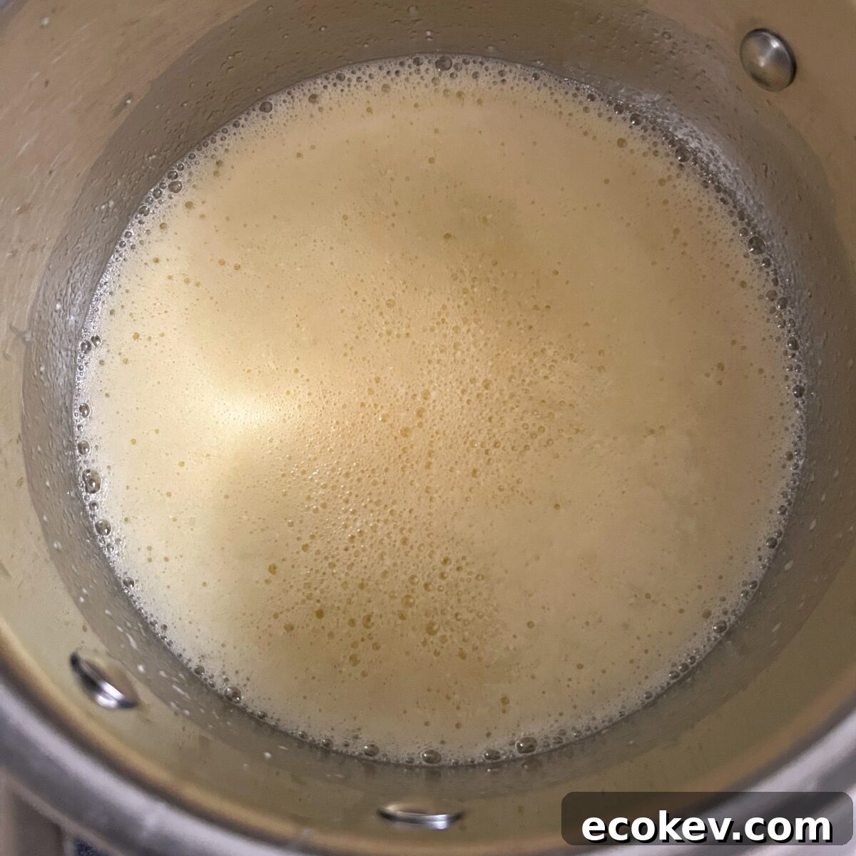 A close-up of a metal pot containing foamy butter.