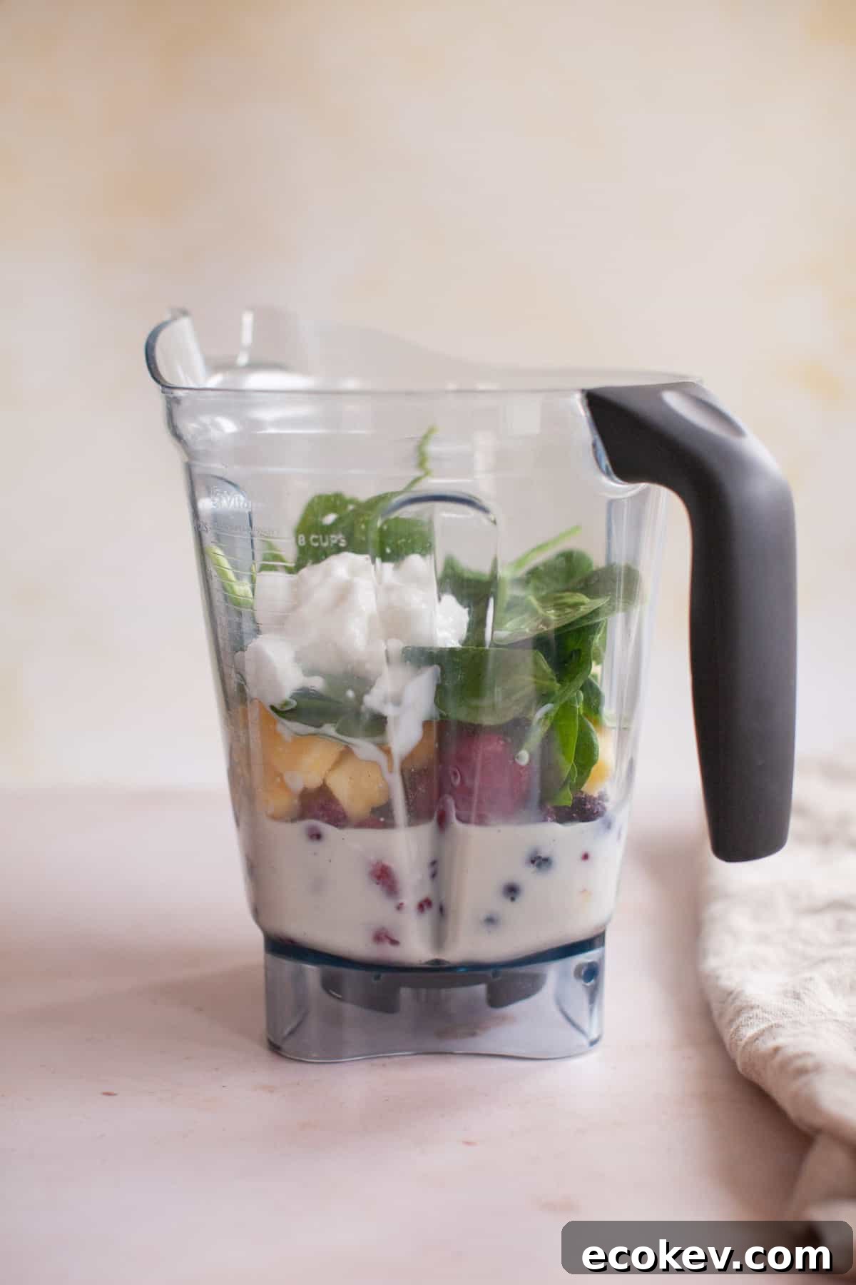 Mixed berries, spinach, yogurt, and almond milk unblended in the blender.