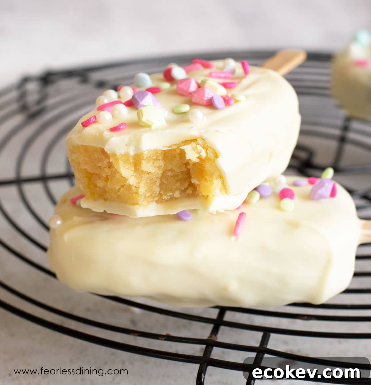 A white chocolate covered cakesicle with a bite taken out.